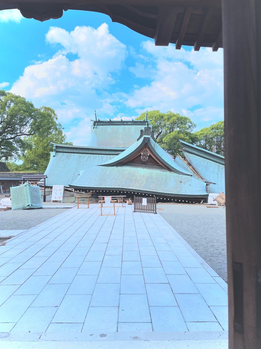 晴れた空の下、被災した神社の社殿。境内には修復のための資材が置かれている