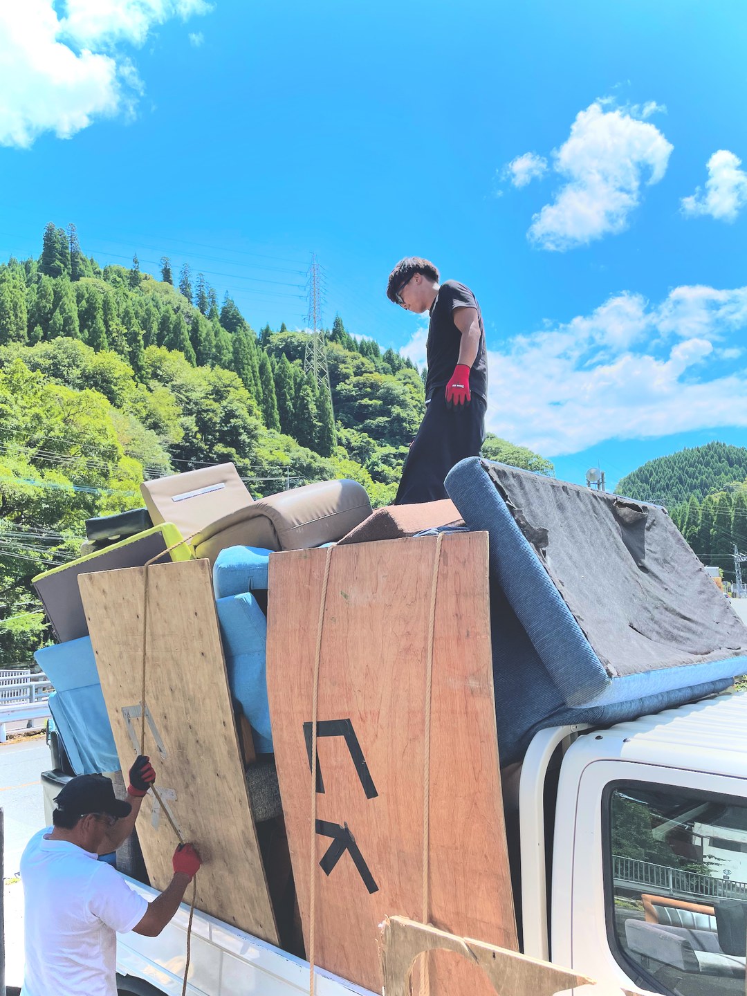 軽トラックの荷台に積み上げられた災害廃棄物。荷台の上と下で2人が積み込み作業をしている